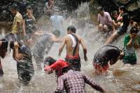 CAMBODIA, Siem Reap. Water fight amongst local people picnicking & swimming at waterfall, Phnom Kulen.