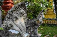 CAMBODIA, Siem Reap. Modern Naga serpent statues and burial stupas in monastery garden, Puok district.