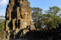 CAMBODIA, Siem Reap. Some of 216 carved stone faces at Bayon temple, built in late 12th century by Buddhist King Jayavarman V11 as centre of his capital of Angkor Thom. Sunset.