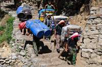 NEPAL. Porters passing on Everest Basecamp trail; expedition porters returning (with barrels) & porters with beer supplies going up.
