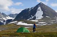 NORWAY, Troms, Lyngsalpan (Lyngen Alps). Hiker camped at Lomvatnan lakes, Kaulddalen valley & peaks beyond.
