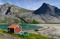 NORWAY, Nordland. Lofoten Islands, Moskenesoy. Shack at Bunes beach, with granite cliff face on Helvetestinden opposite.