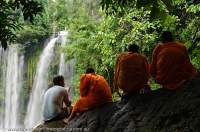 CAMBODIA, Siem Reap. Monks on boulder at waterfall, Phnom Kulen.