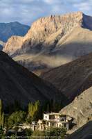 Traditional style Ladakhi house on irrigated valley floor, barren slopes of Ladakh Range above.