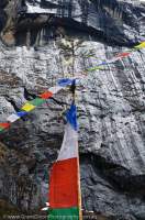 NEPAL. Prayer flags & glaciated granite bluff, Barun valley, Makalu Base Camp Trek, Makalu - Barun National Park.