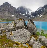 NORWAY, Troms, Lyngsalpan (Lyngen Alps). Moraine boulders at Blavatnet, water colour due to fine suspended glacial silt.